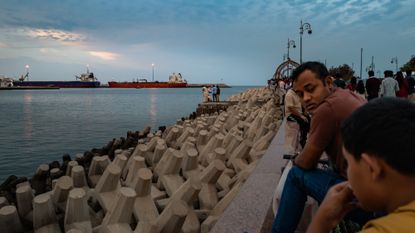 People watch oil tankers sail into port in Muscat, Oman.