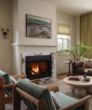 beige living room with marble fireplace and blue armchairs