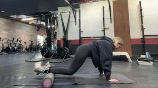 Woman balancing legs on foam roller in modified plank position.
