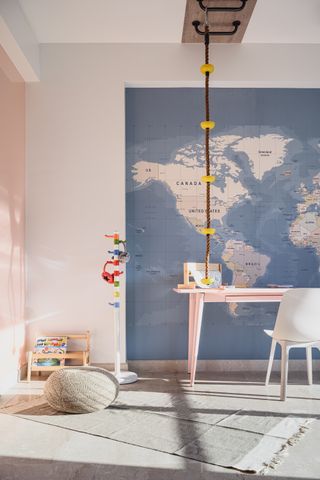 A bedroom with a study table, a wold map wallpaper and a monkey ladder
