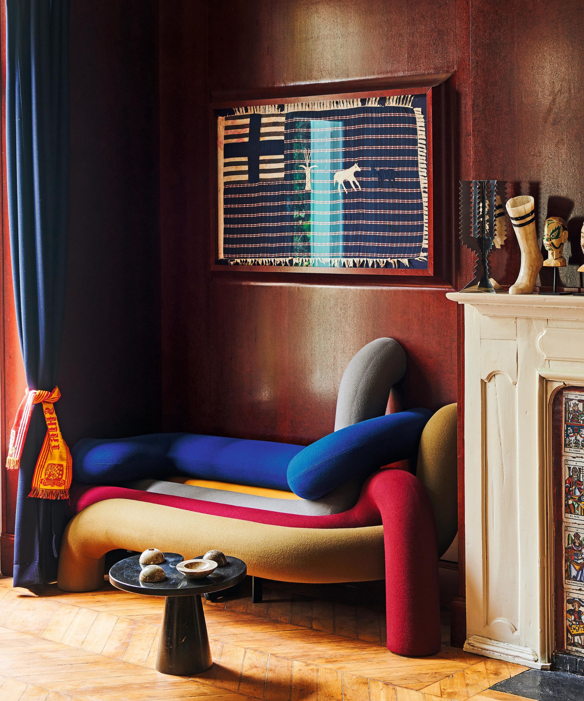 a moody dark red sitting room in paris with a multi colored sculptural couch