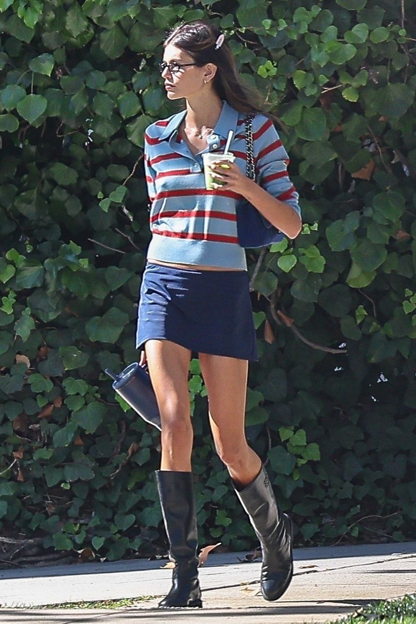Kaia Gerber wearing a striped polo sweater, white T-shirt, miniskirt, and knee boots in L.A. during August 2025