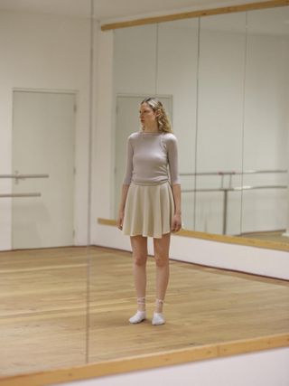 Woman in dance studio in pale cashmere skirt and vest