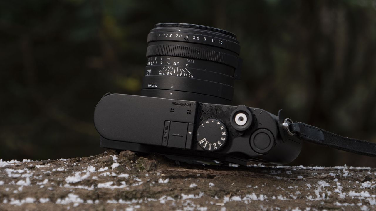 Leica Q3 Monochrom compact camera outside on a snow-dusted log