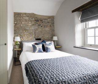 Small master bedroom with exposed stone wall
