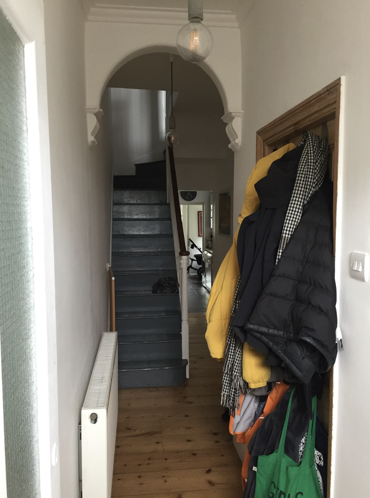 A before shot of a cramped entrance hallways with coats hanging up