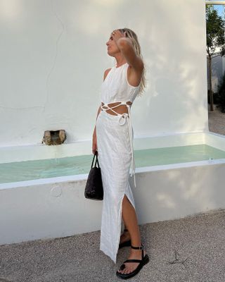 British fashion influencer Lucy Williams poses at a resort wearing a cutout tie front lace up white dress and black platform sandales