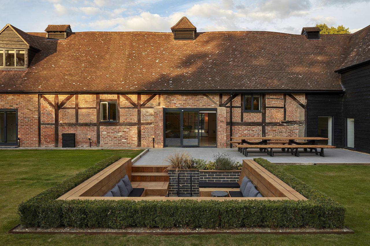 large brick barn conversion with open bifold doors and sunken garden seating