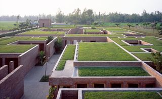 Red brick, square buildings have grass on top of their flat roofs.