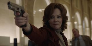 Jean Smart aiming her gun in a bank in Watchmen.