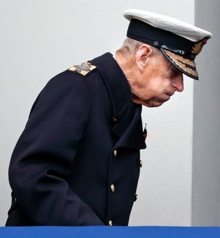 Prince Philip wearing a military uniform and puffing his cheeks out in pain