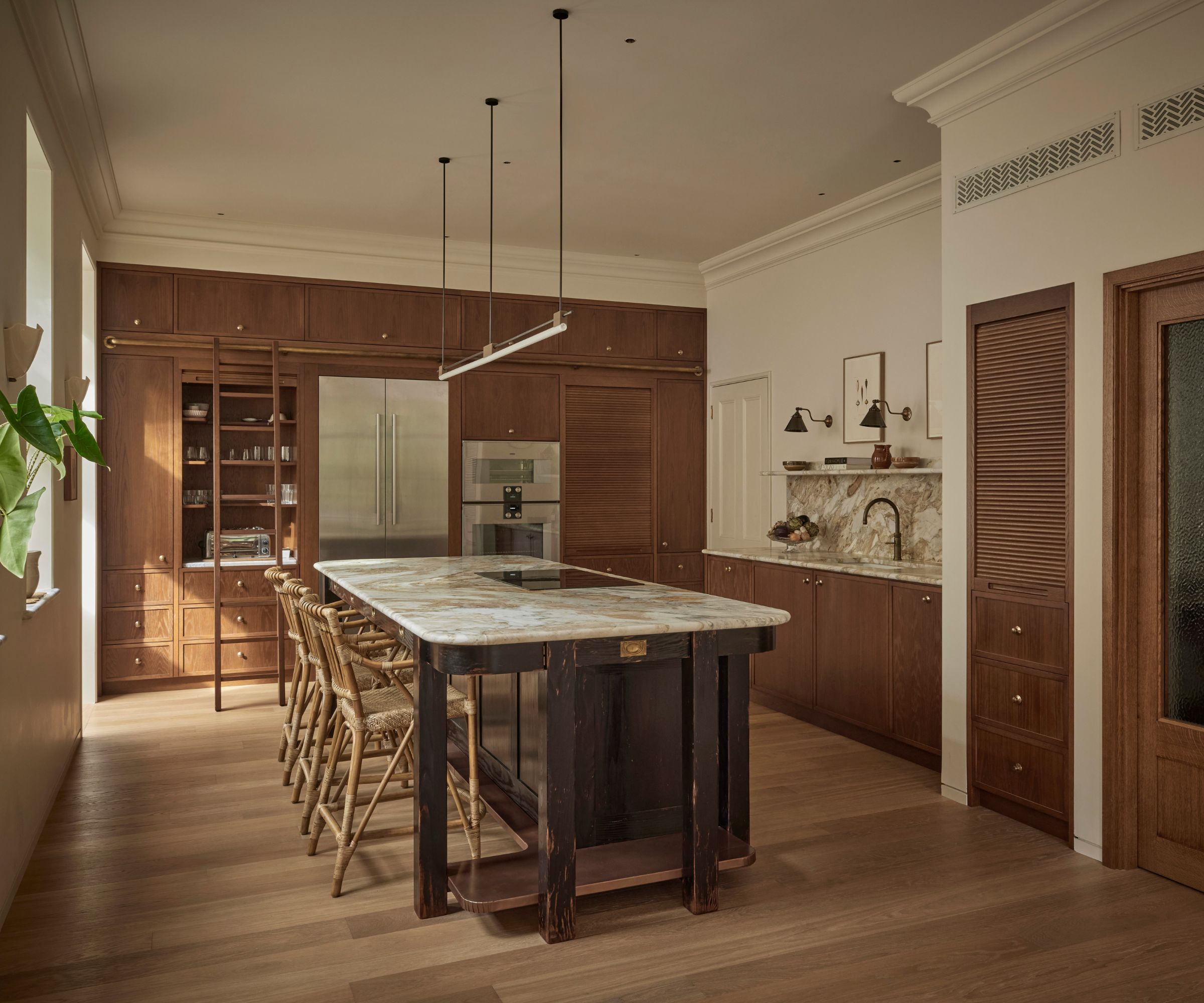 A large kitchen with mid-toned wood cabinets and a dark wood kitchen island