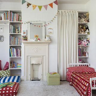 childrens bedroom with white wall and white fire place with small white bed and curtain with toys and books