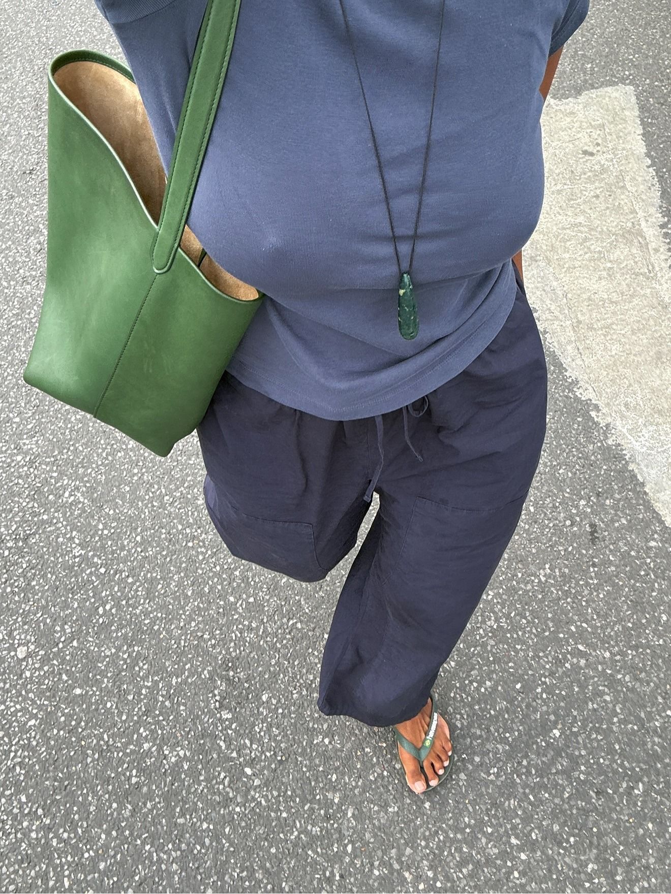 Woman in navy top, pants, and green pendant
