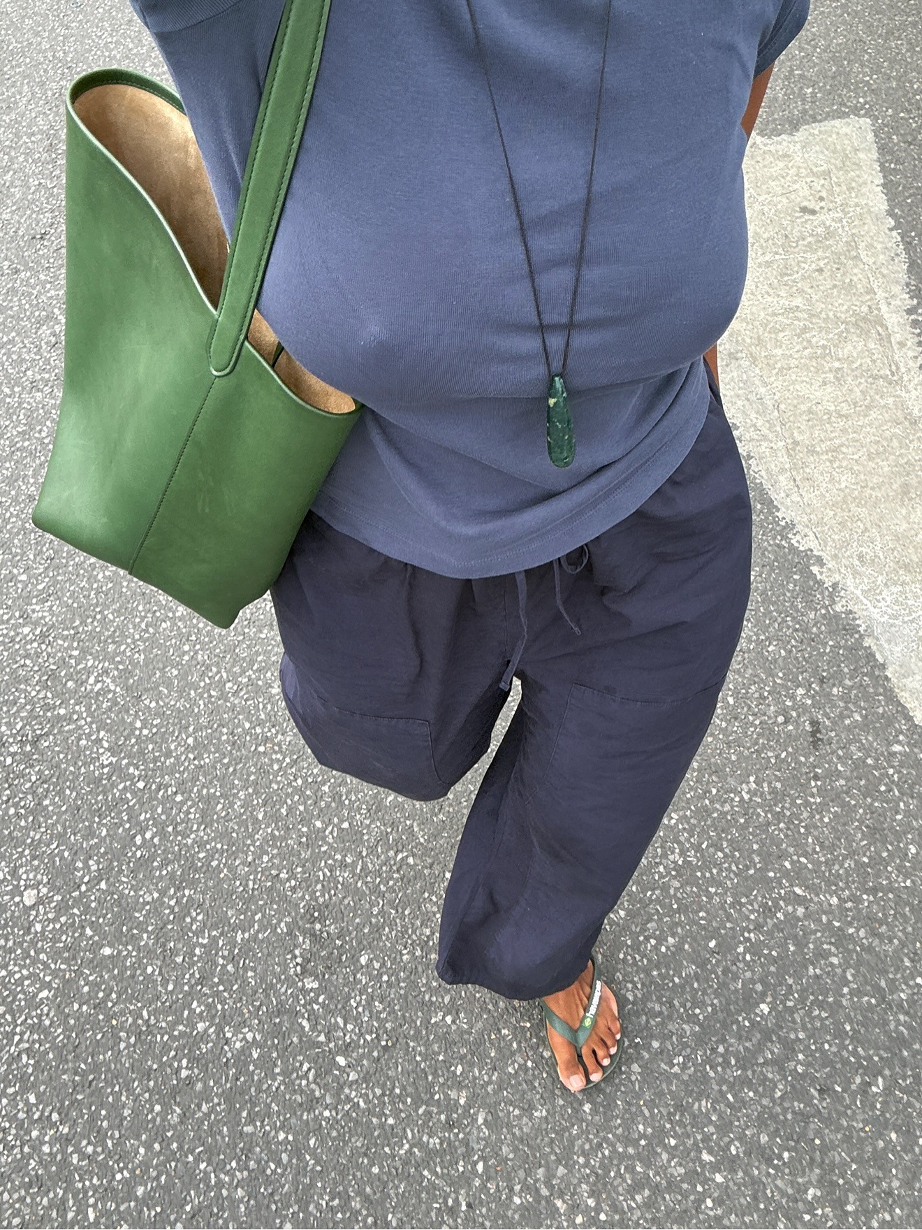 Woman in navy top, pants, and green pendant