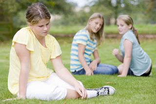 A young teen girl is left out of a conversation by her peers.