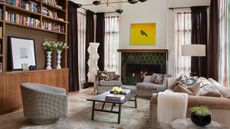 eclectic living room with green tile fireplace, timber cabinets, a caramel sofa, paper lantern and check swivel chair