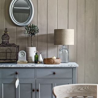 room with grey striped wall grey drawers and mirror on wall