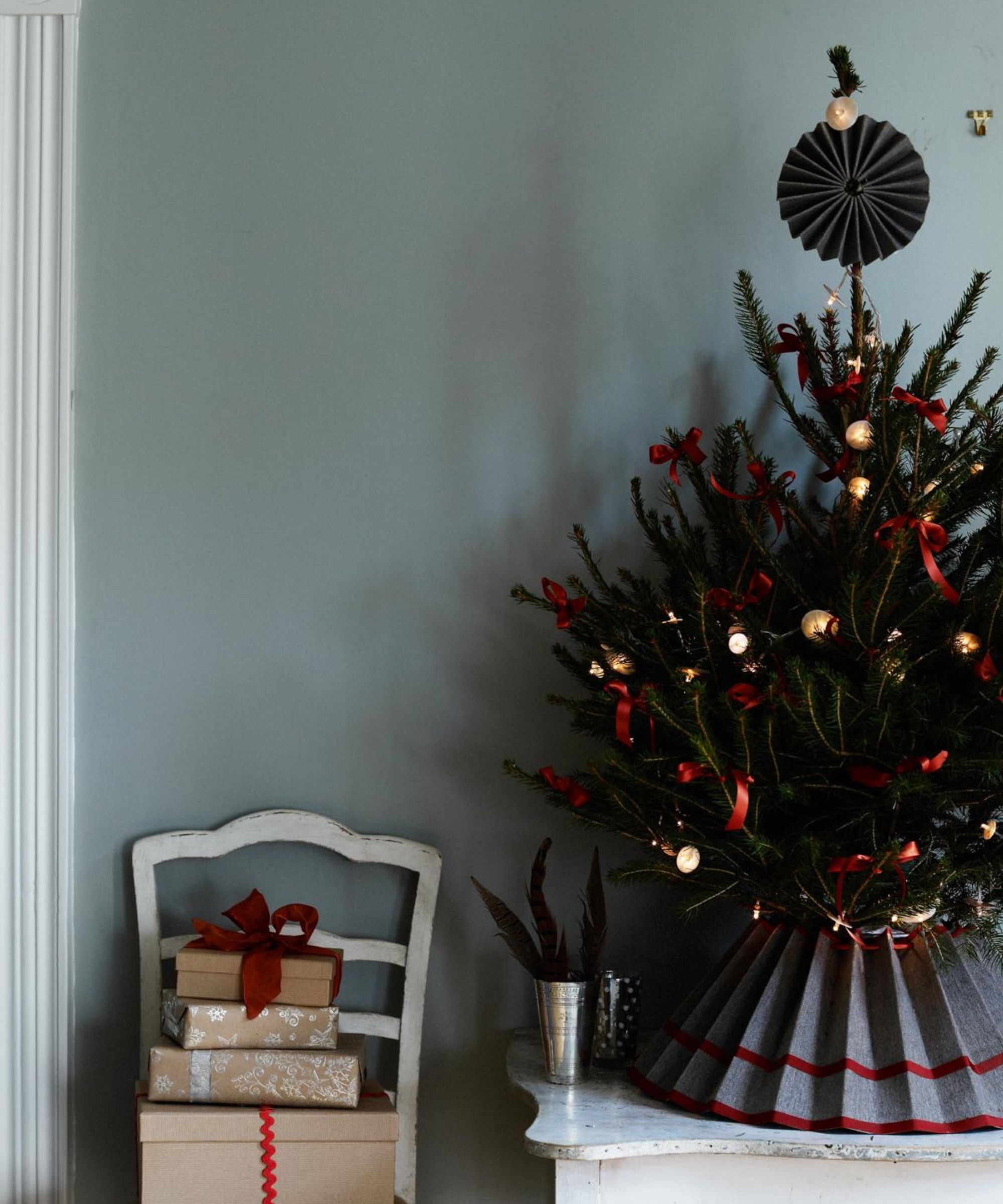 small christmas tree with red and gold decorations and gray skirt