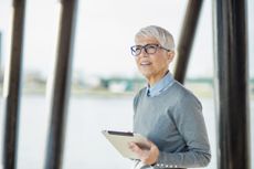 Portrait of a senior woman, she is smiling and holding a tablet