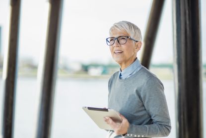 Portrait of a senior woman, she is smiling and holding a tablet