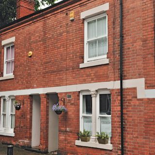 Exterior of red brick terraced houses with hanging baskets