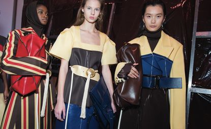 Models wear striped trenches, short sleeved top with squared cleavage, leather skirt, polo neck, leather bags and metal hoop earrings.