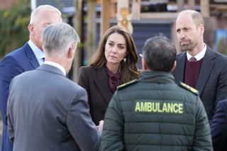 Kate Middleton and Prince William talking to emergency services personnel in a circle