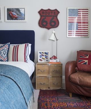 A teenage boy's bedroom with red and blue furnishings and artwork, with an aged leather armchair.