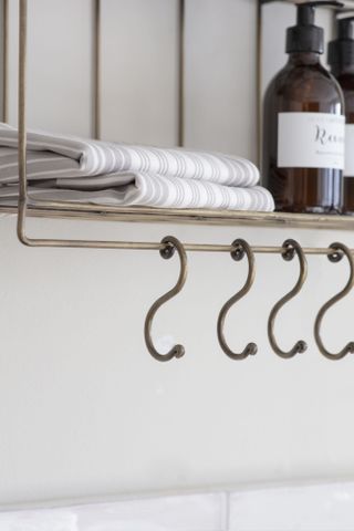Curved metal hooks hanging off a shelving unit storing folded linen