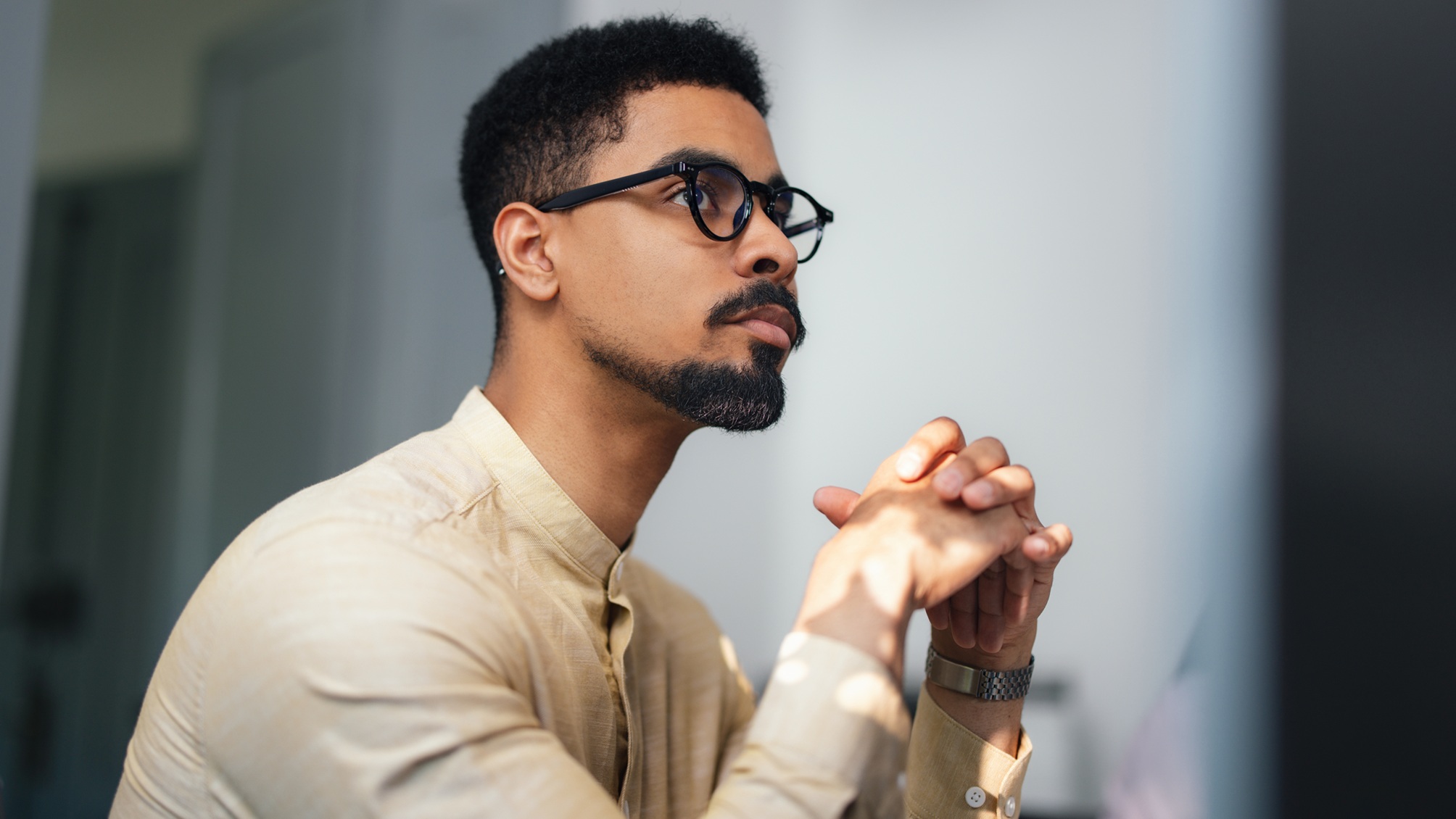 A man appears thoughtful as he looks into the distance in his office. 