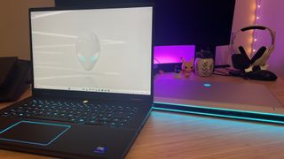 Alienware M16 gaming laptop open on a wooden desk with Alienware X16 behind it