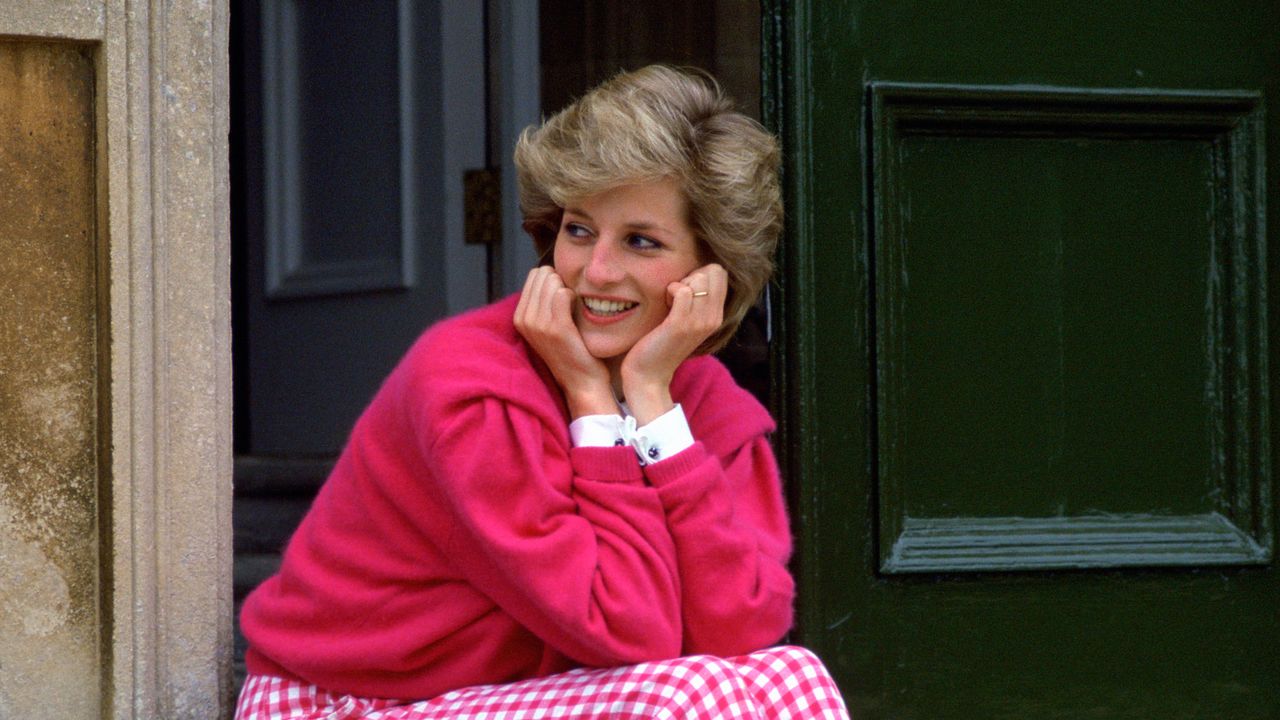 Diana, Princess Of Wales, Sitting On The Steps Outside Her Country Home, Highgrove. The Princess Is Casually Dressed In Pink Gingham Trousers With A Matching Pink Jumper.