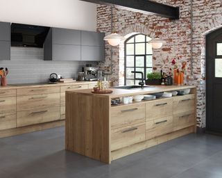 A natural oak kitchen with peninsula and exposed brick wall