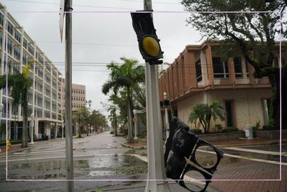 The after effects of Hurricane Ian in florida show a broken traffic light and fallen down trees