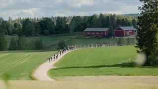 A large group of gravel riders in smooth finish gravel roads