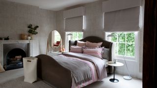 drey and ourple master bedroom wiith bed placed centrally below windows with blinds covering windows to follow Feng Shui