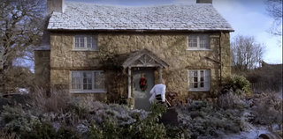 A still from 2006 movie The Holiday starring Cameron Diaz showing the film's idyllic English Christmas cottage in the countryside covered in snow