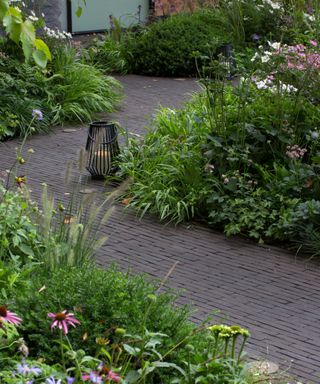 zig zag paving stone garden path surrounded by flower borders