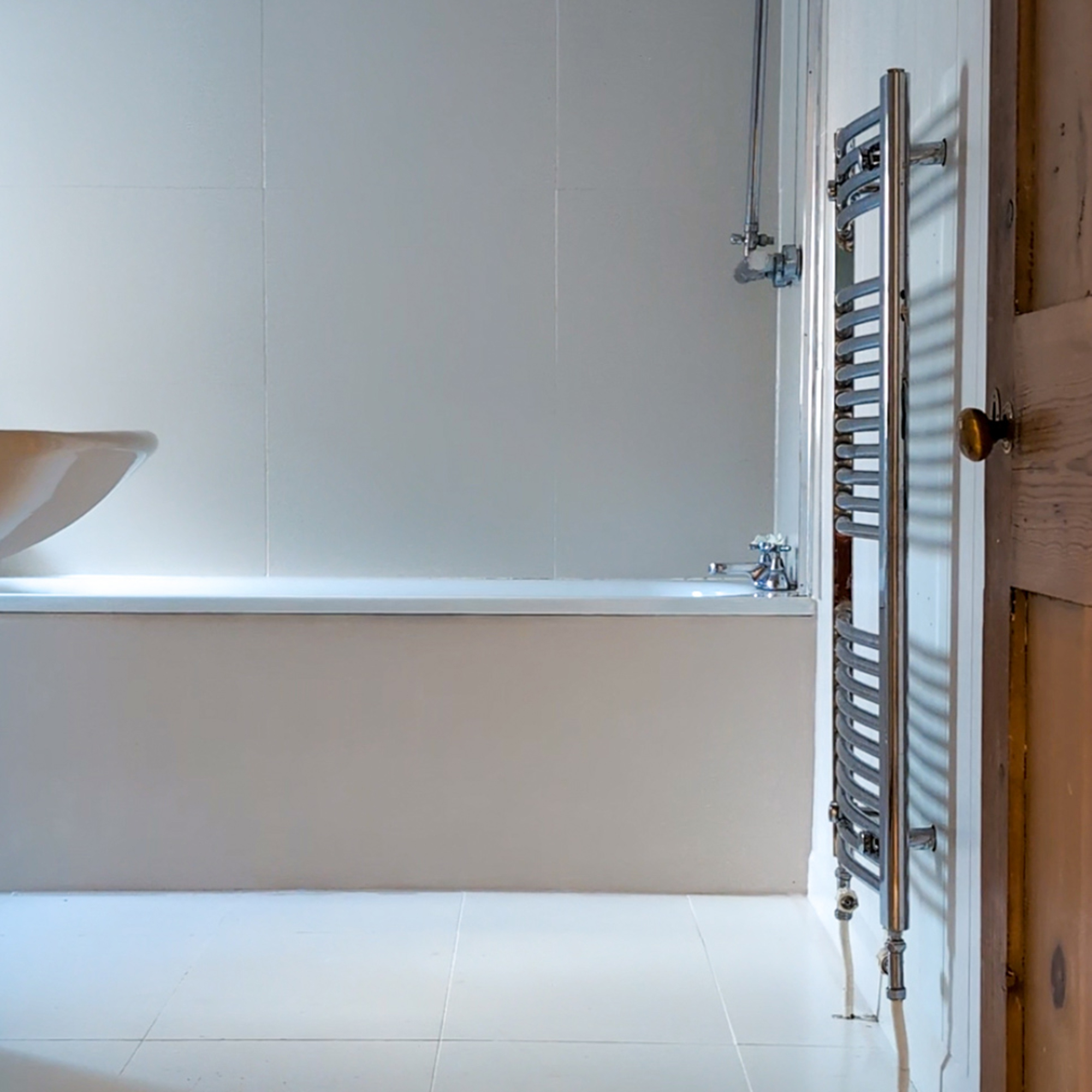 plain beige bathroom with fitted bath and chrome towel rail