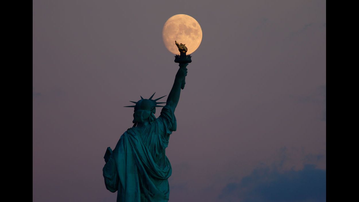 A nearly full moon rises above the Statue of Liberty in New York on Sept. 18. 2021.