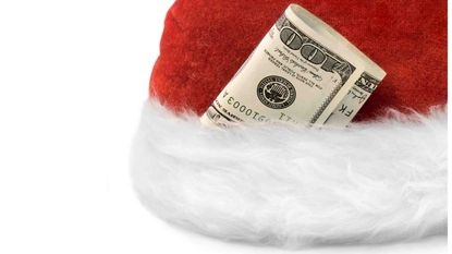 Photo of the brim of a Santa hat with folded up currency tucked in the fur.