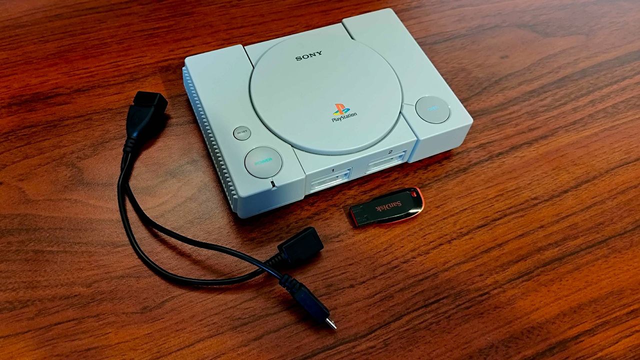 PS1 Mini next to Sandisk USB drive and OTG cable on woodgrain desk