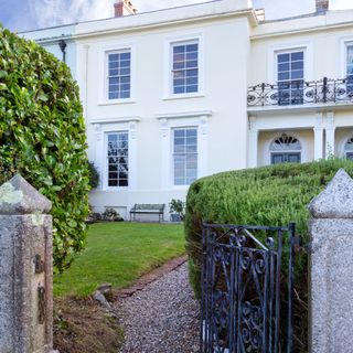 Small walled front garden lawn with gravel path and iron gate