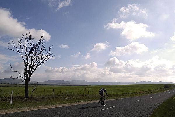 All by myself: A lone rider on the tour buries his head and makes the most of the sun as he heads for hills in the background.