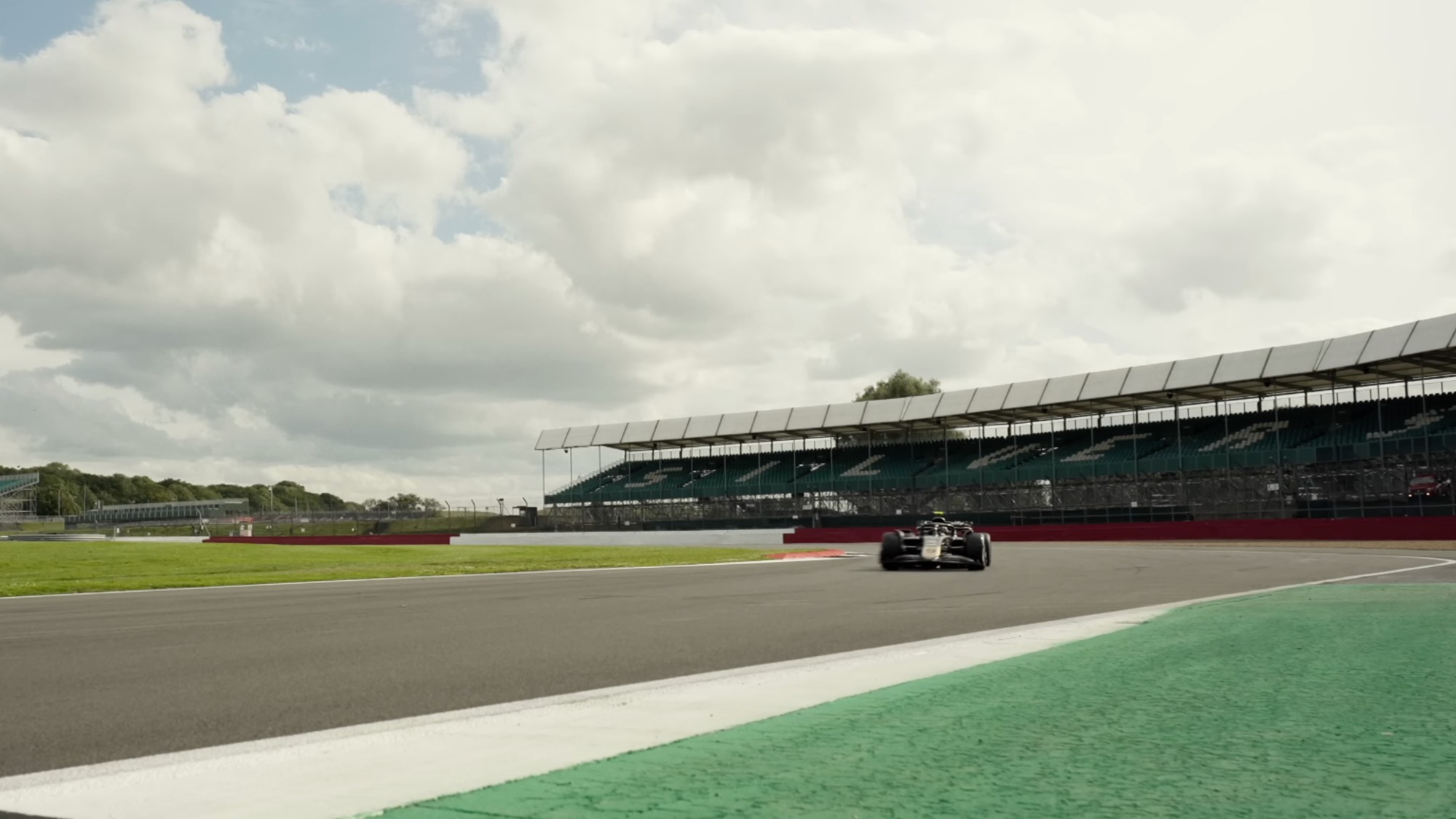 A black F1 car going around a corner on a race track in F.