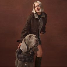 Model wearing a brown jacket and boots sold at New Look in front of a grey ridgeback dog