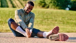 Runner suffering from foot pain sitting on ground