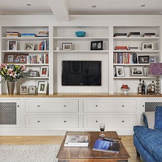 living room with smart tv on wall and white wooden shelves