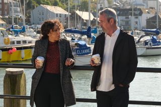 DS Jen Rafferty (Pearl Mackie) speaks to Christopher Reasley (Neil Morrissey) at the marina. They are leaning back on the safety rails and both holding cups of takeaway coffee.